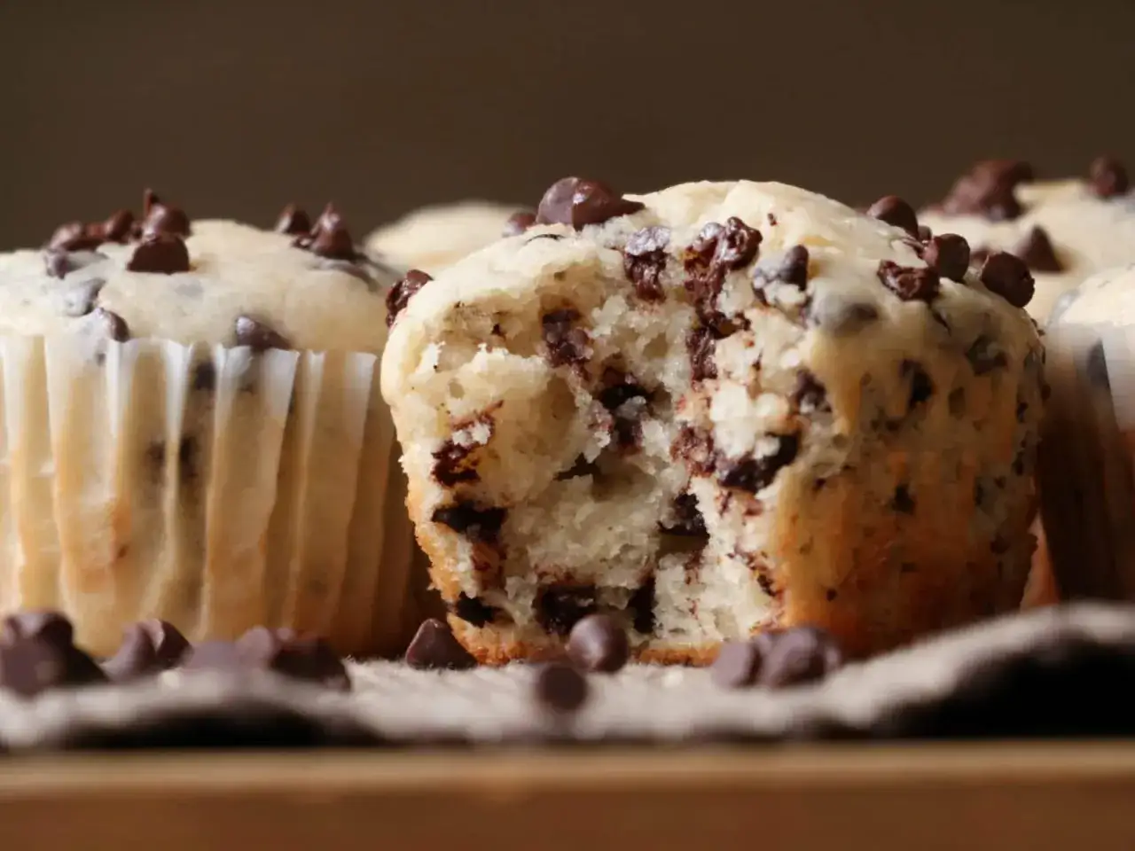 Saftige Schokomuffins, perfekt f&uuml;r ein schnelles schokomuffins rezept. Ein Muffin ist angeknabbert und zeigt die vielen Schokost&uuml;ckchen.