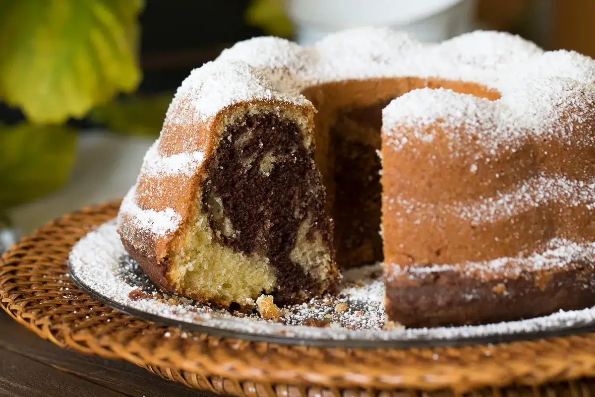 Ein saftiger Marmorkuchen, best&auml;ubt mit Puderzucker, wartet auf seinen Anschnitt.
