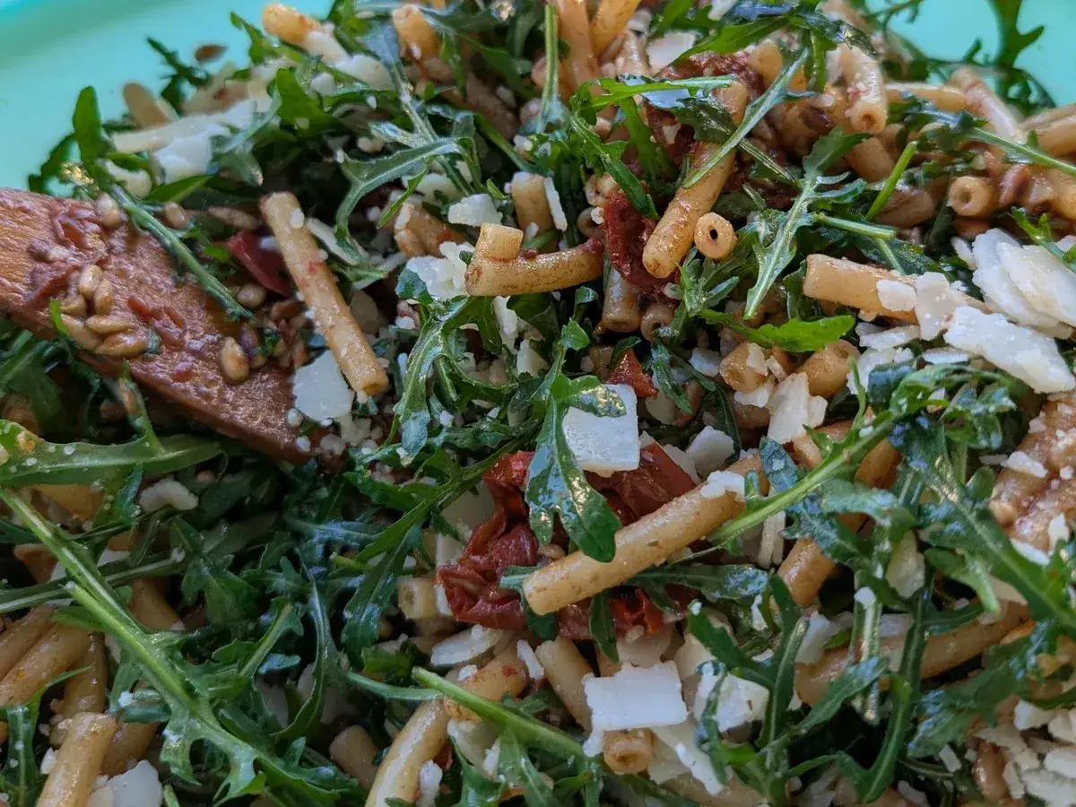 Mediterraner Salat mit getrockneten Tomaten und Rucola, garniert mit Parmesan und Pinienkernen.