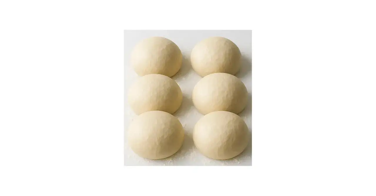 Sechs Kugeln Pizzateig, original Rezept von einem italienischen Gastronomen, liegen auf einer bemehlten Fl&auml;che.