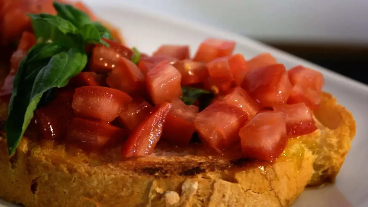 Frisch zubereitete Bruschetta vom Grill mit saftigen Tomatenw&uuml;rfeln und Basilikum auf ger&ouml;stetem Brot.