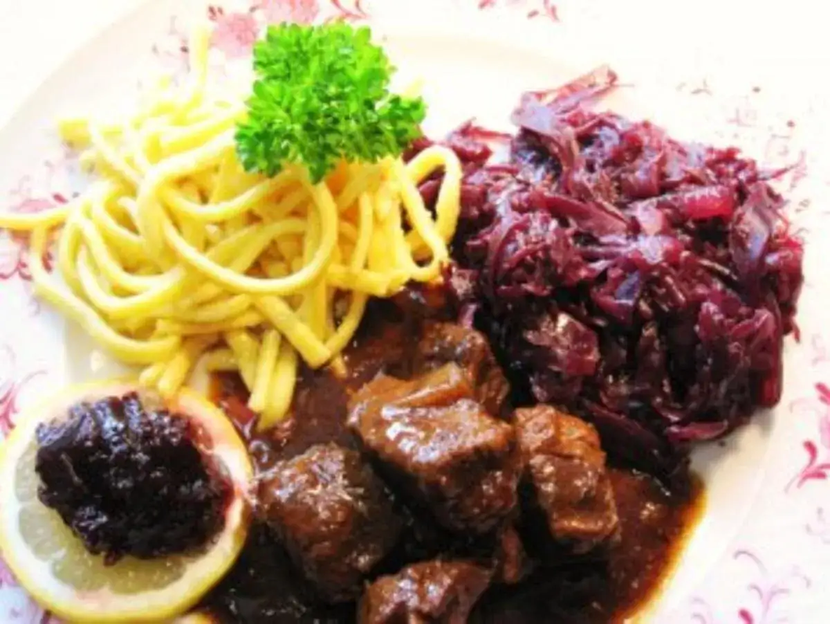 Deftiges Gulasch mit Sp&auml;tzle und einem k&ouml;stlichen rotkohl rezept. Garniert mit Petersilie und einer Zitronenscheibe.