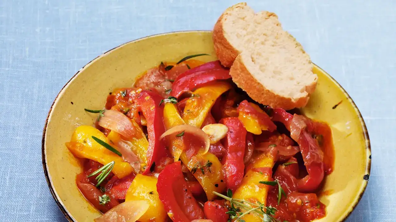 Buntes Peperonata-Gericht mit Paprika, Tomaten und Zwiebeln, serviert mit Brot. Ein authentisches peperonata original rezept.