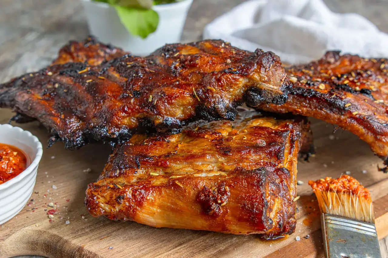 Butterzarte Spareribs im Backofen, glasiert und perfekt gegrillt, mit einer Beilage scharfer Sauce und einem Pinsel zum Nachglasieren.
