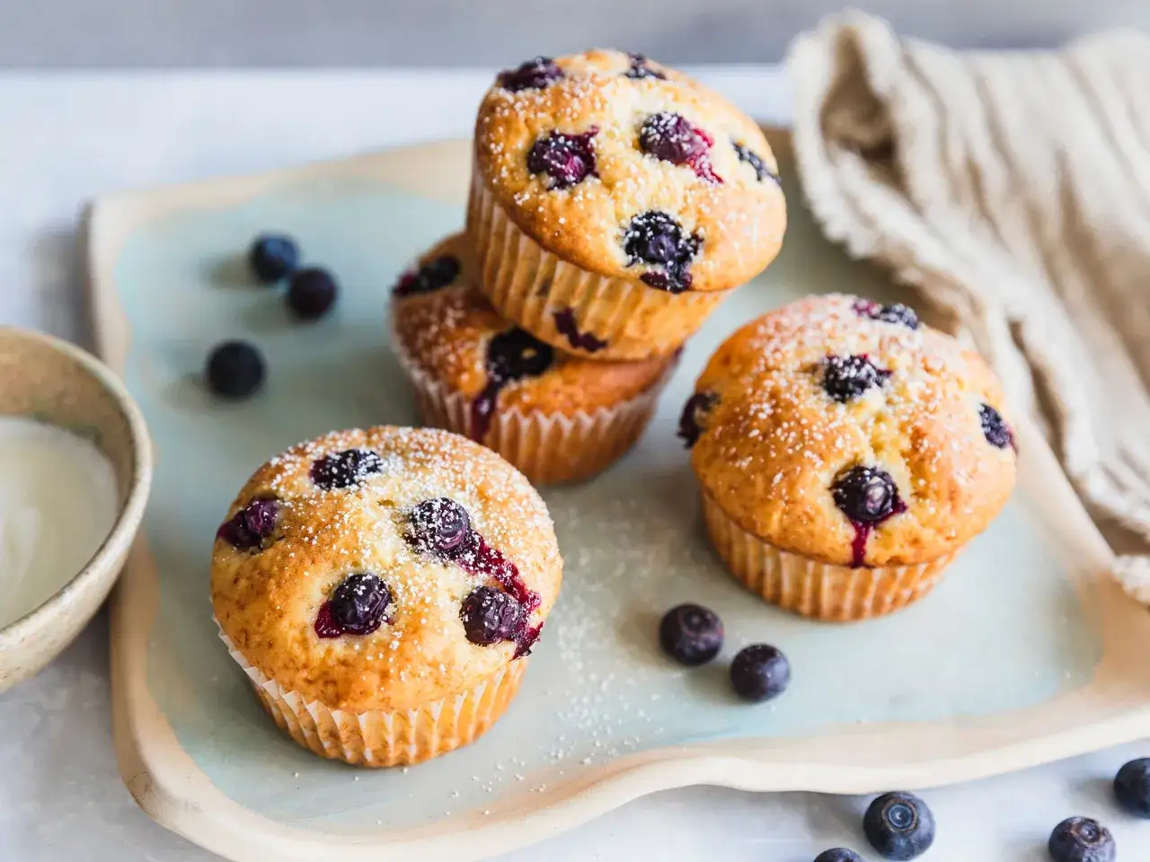 Saftige blaubeermuffins mit Joghurt, best&auml;ubt mit Puderzucker, liegen auf einem Teller.