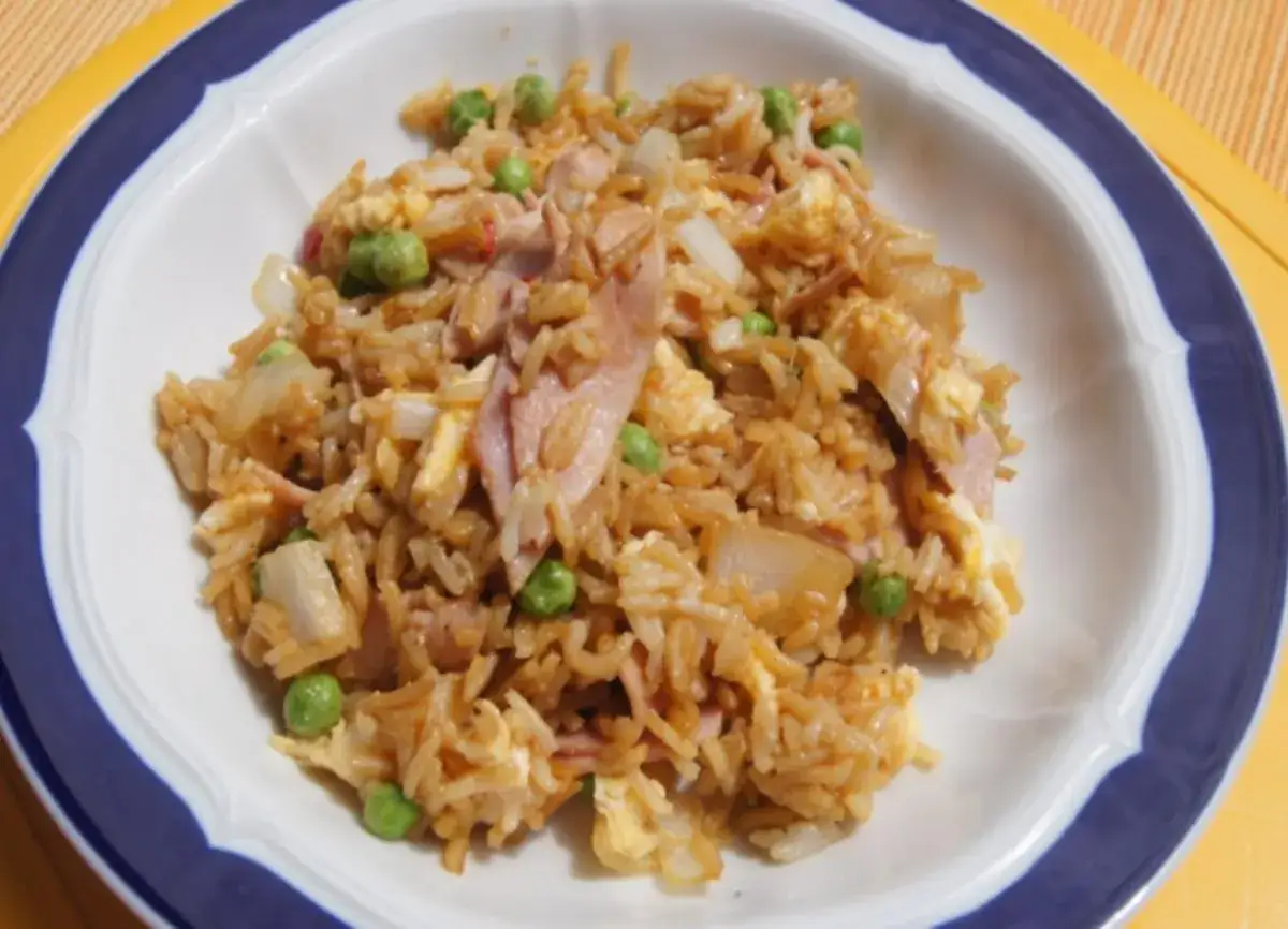 Gebratener Eierreis wie beim Chinesen, mit Erbsen und Schinken, in einer weißen Schüssel mit blauem Rand.