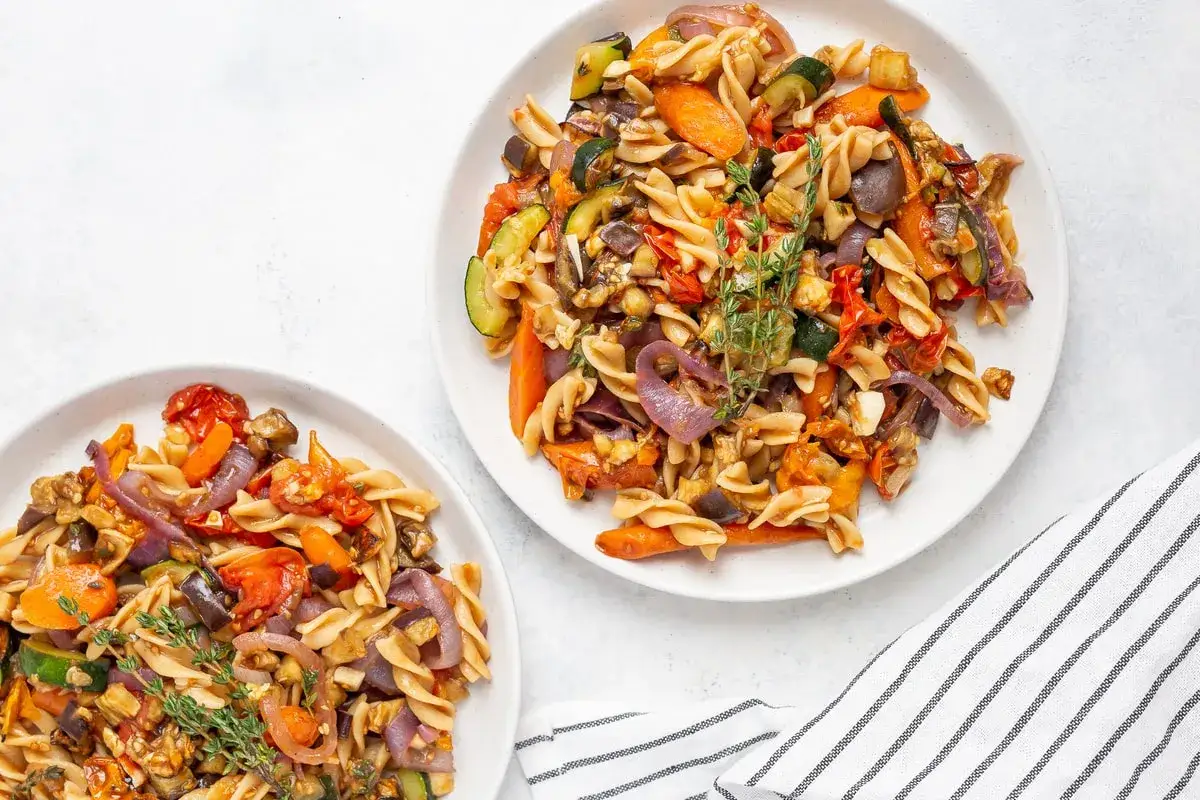 Zwei Teller Nudelpfanne mit viel Gemüse wie Zucchini, Karotten, Tomaten und Zwiebeln. Leckere Rezepte bei Gicht, die schmecken und guttun.