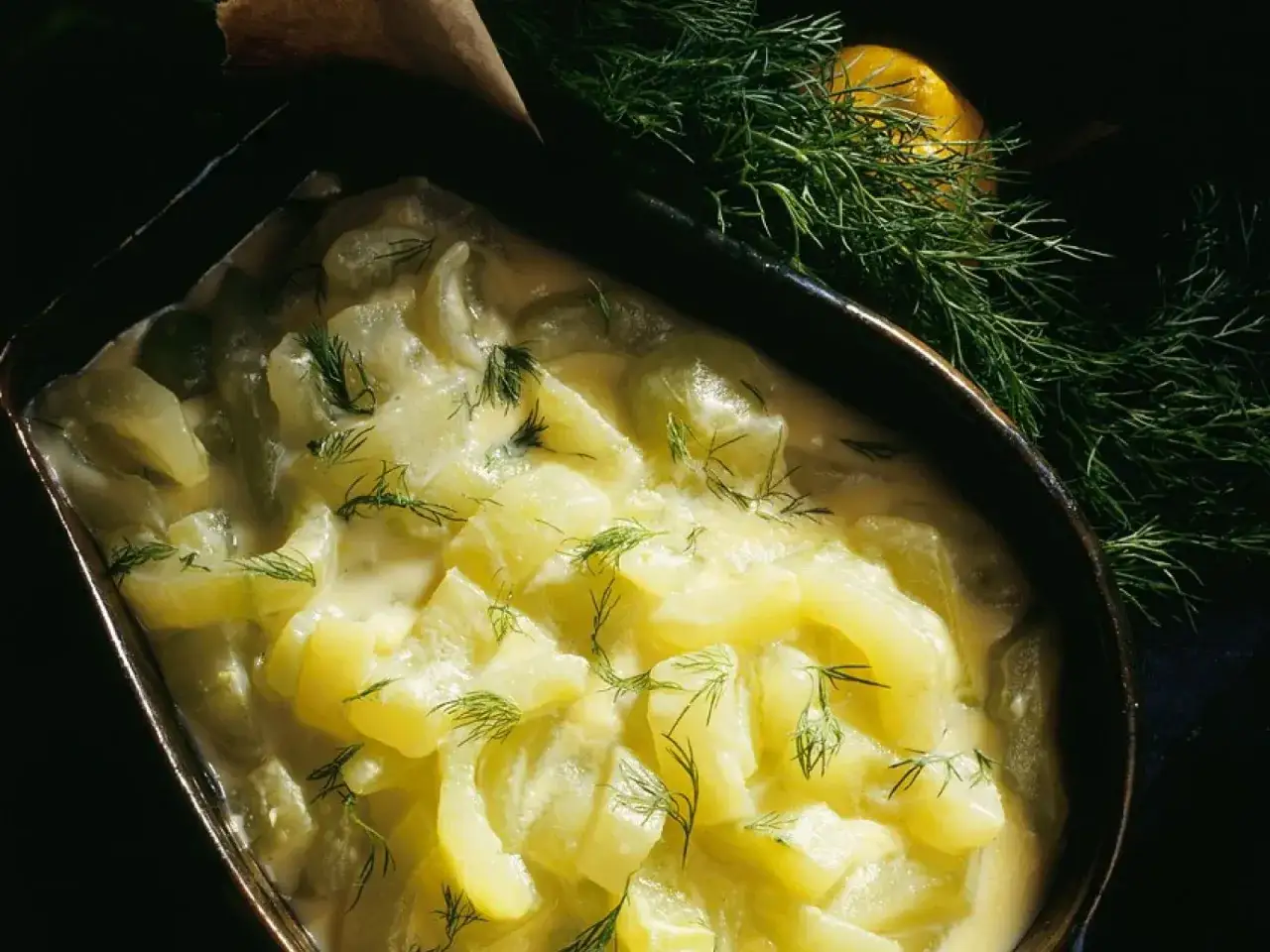 Schmorgurken in cremiger So&szlig;e, garniert mit Dill. So sehen sie aus, appetitlich und frisch, mit einem Hauch Zitrone im Hintergrund.
