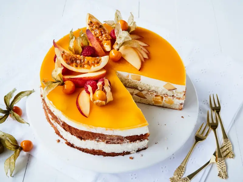 Eine köstliche Pfirsich Maracuja Torte, verziert mit frischen Früchten und Physalis. Ein süßer Genuss für besondere Momente.